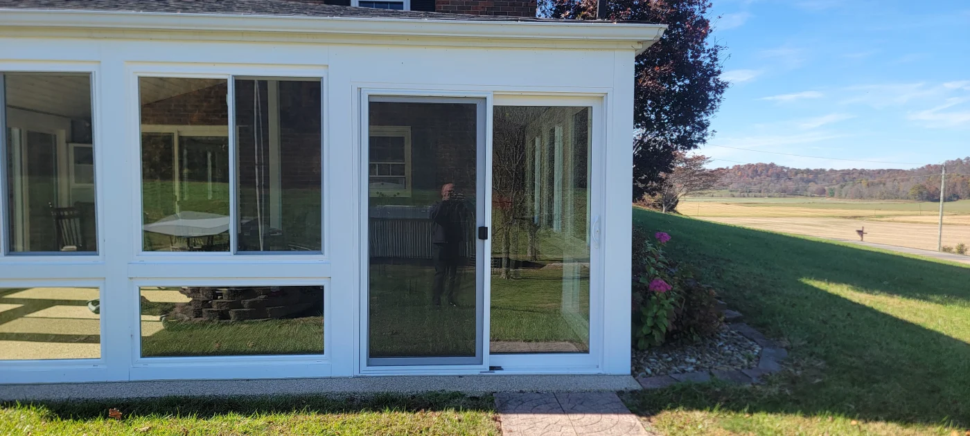 A glass patio enclosure allows natural light into an outdoor living area in Petersburg, IN.